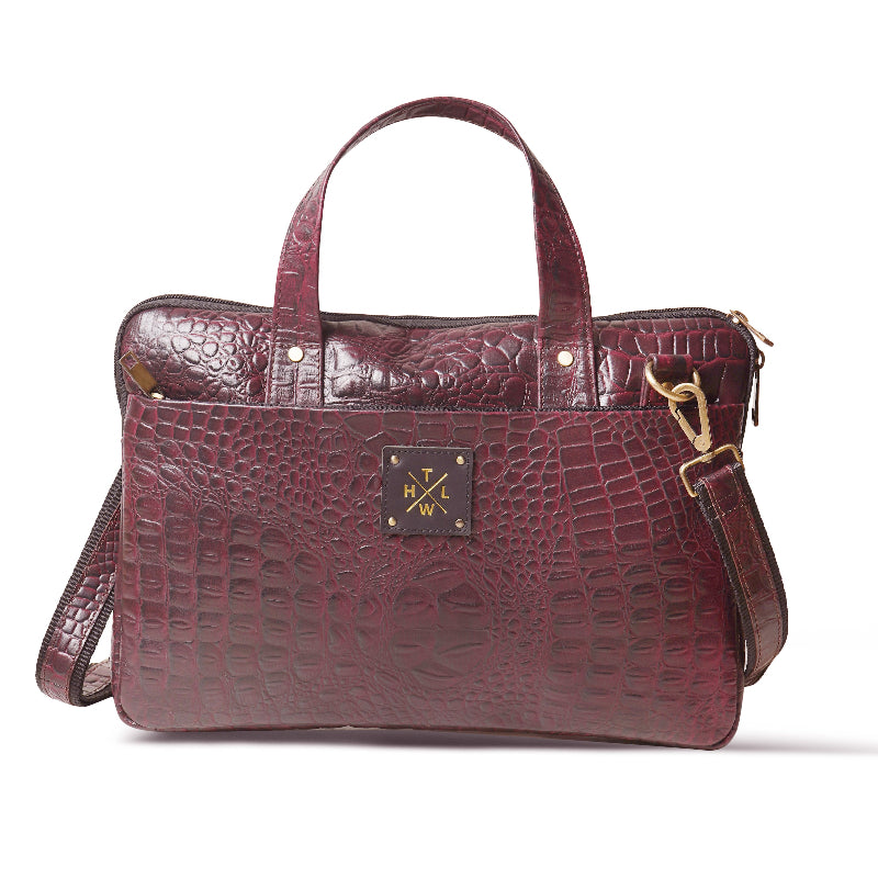Maroon crocodile-patterned handbag with gold hardware on a white background