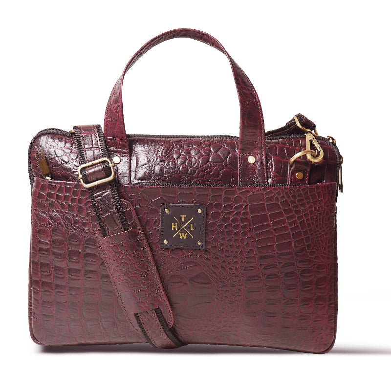 Maroon crocodile-patterned handbag with gold accents on a white background