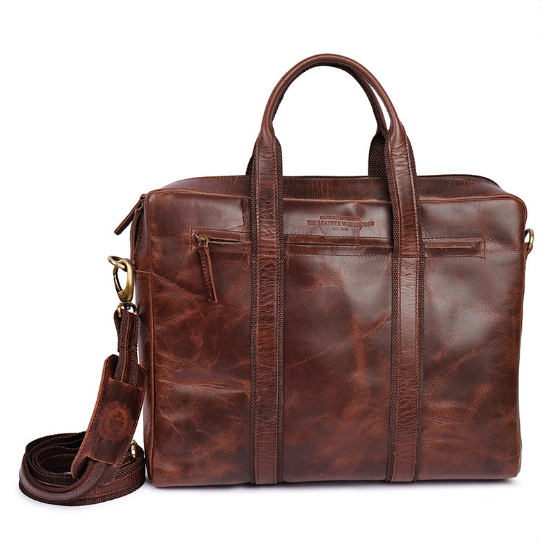 Premium brown leather laptop bag with dual handles and detachable shoulder strap from The Leather Warehouse featuring front zipper pockets and a polished finish.