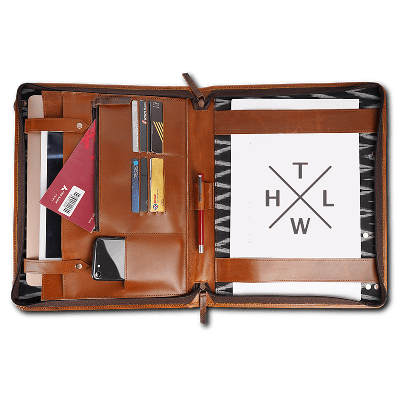 Open brown leather file folder with laptop pocket zippers pen holder and office supplies arranged