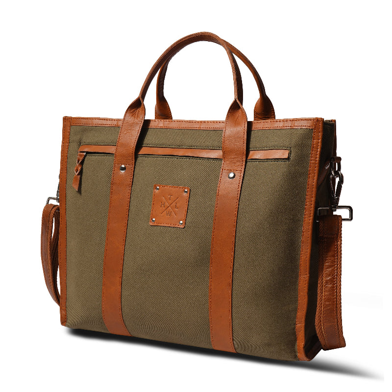 Green bag with brown leather straps and handle on a white background