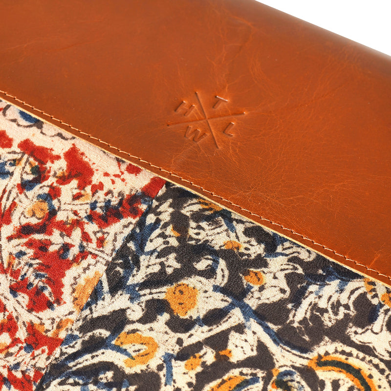 Close-up of a patterned fabric with a brown leather border and a logo.