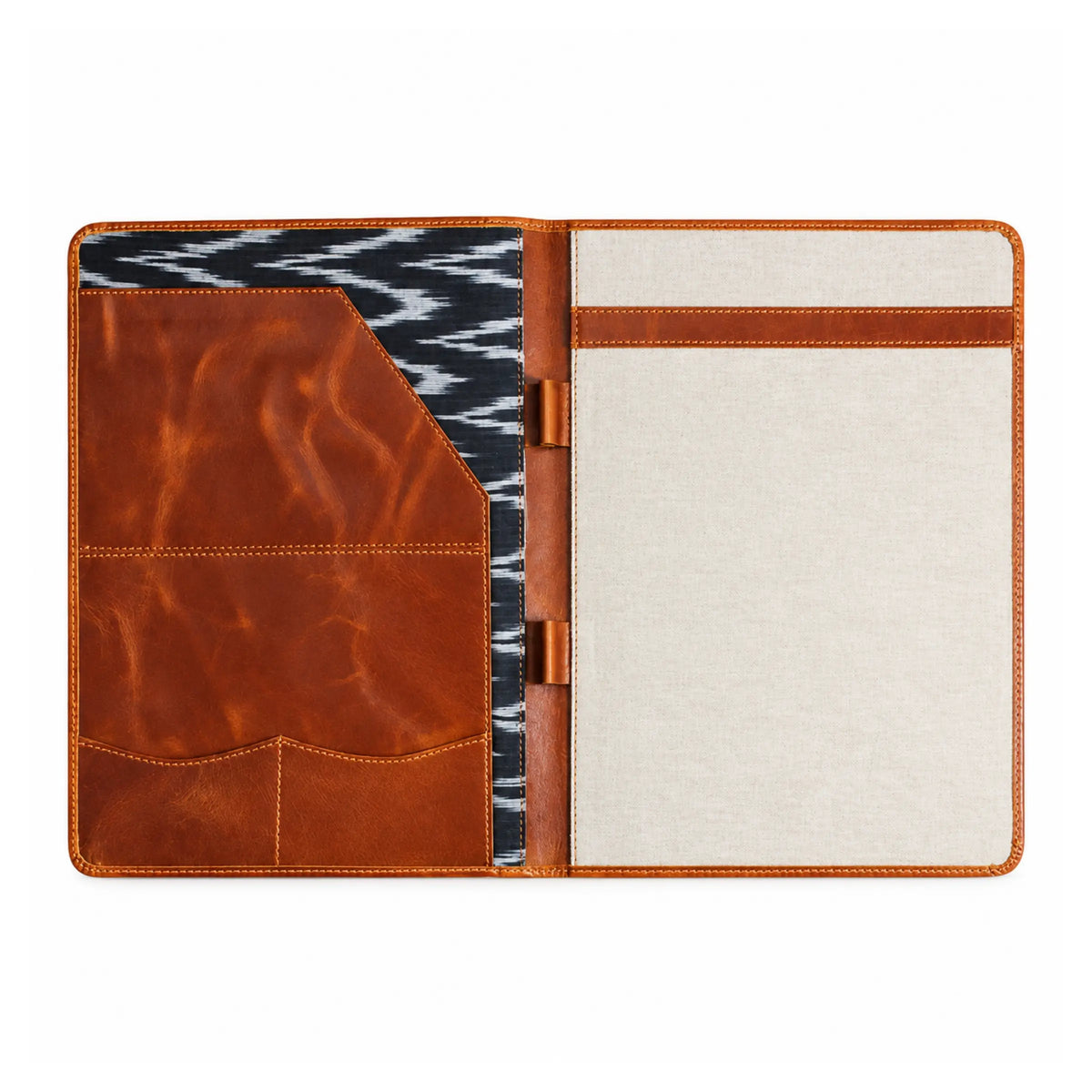 An open leather notebook cover with a warm brown leather exterior, a cream fabric interior page, a brown horizontal card slot band, and a black-and-white patterned fabric pocket on the left side.
