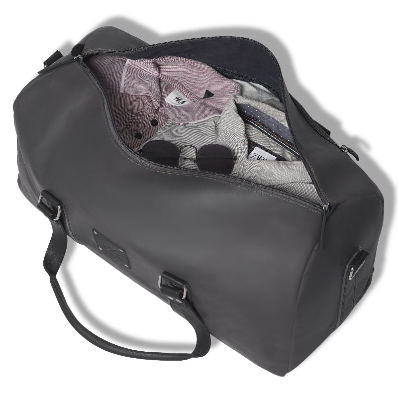 Gray duffel bag with clothes partially packed on a white background