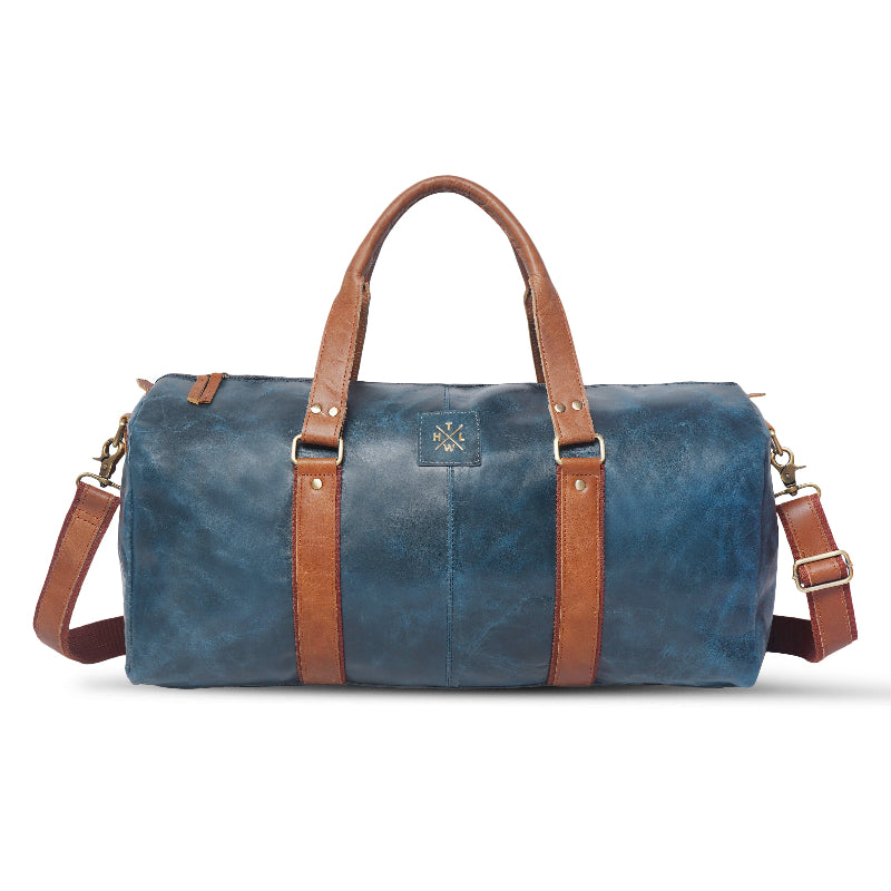 Blue duffel bag with brown straps and handle on a white background