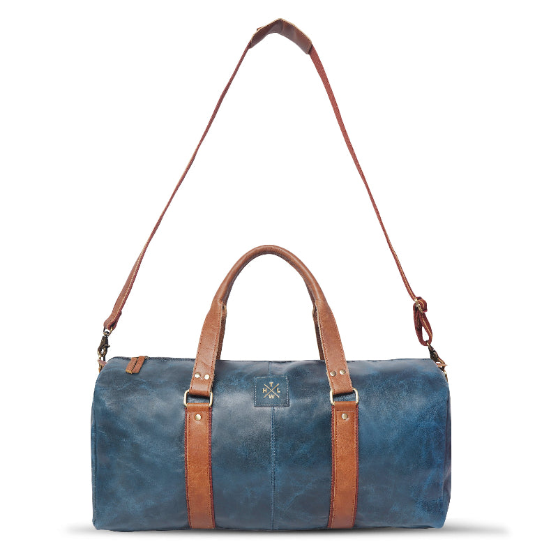 Blue duffel bag with brown leather straps on a white background