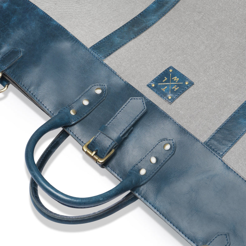 Blue leather bag with gold hardware on a gray background