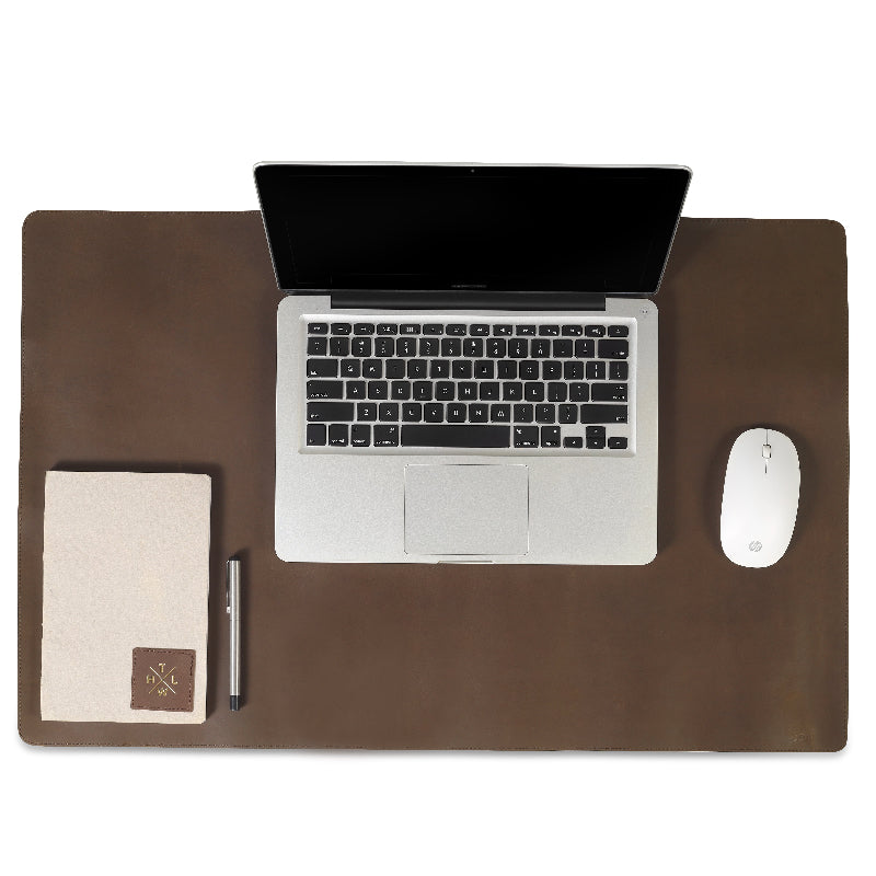 Laptop on a brown leather desk with a mouse and notebook