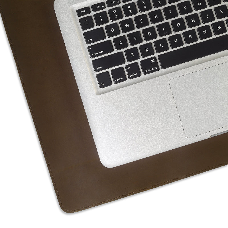 Laptop on a brown leather desk pad with a white background