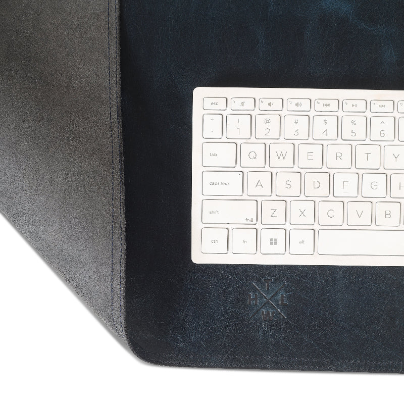 Black leather desk mat with a white keyboard on top