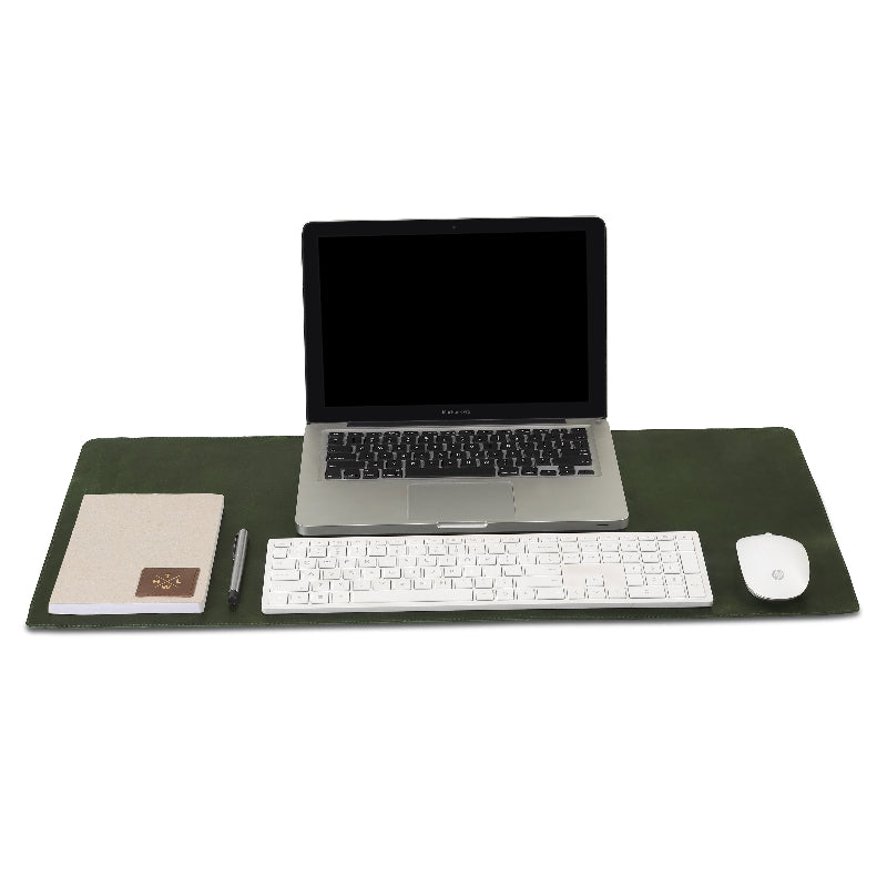 Laptop, keyboard, mouse, and stationery on a large desk pad with a white background