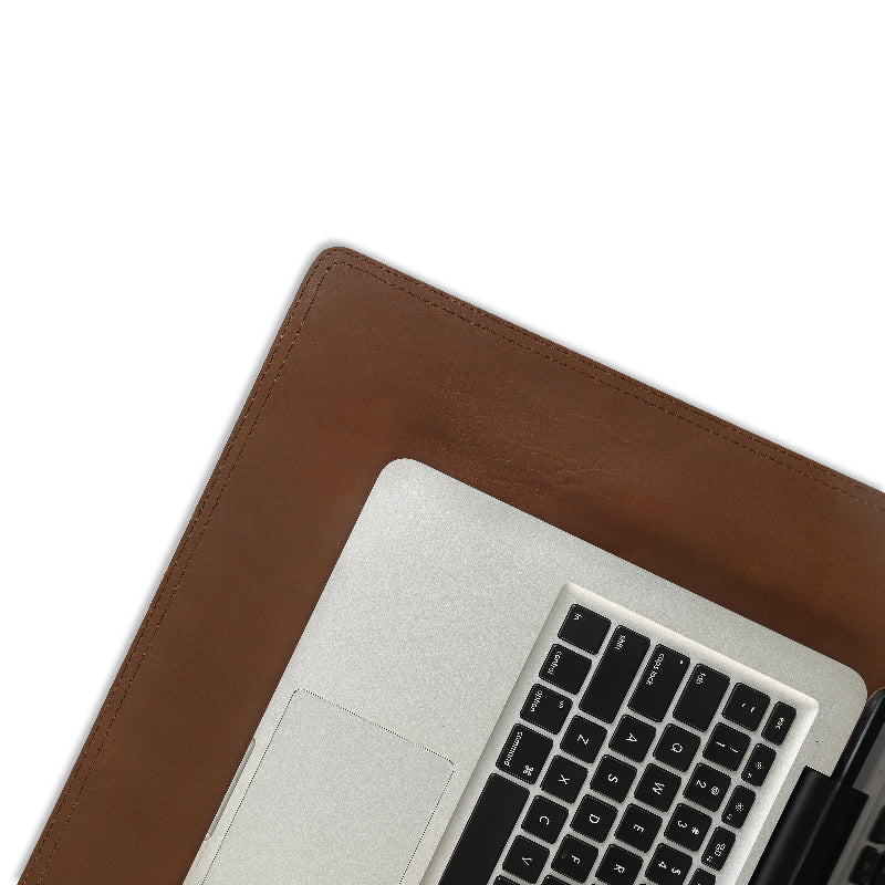 Laptop on a brown leather desk mat  with a white background