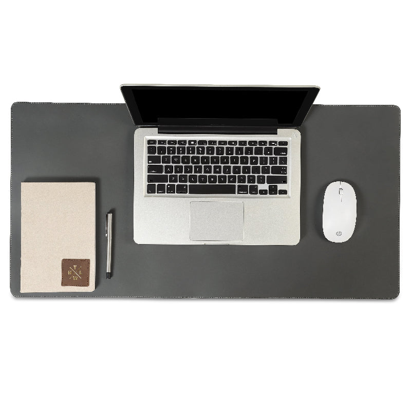 Top view of laptop on grey leather desk mat with mouse notebook and pen