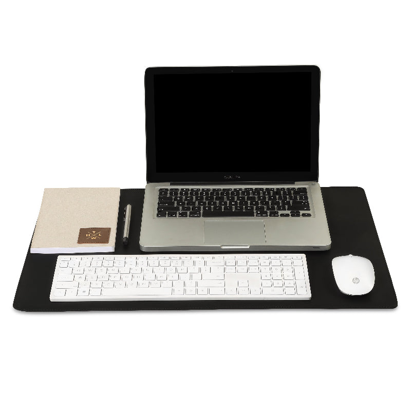 Laptop, keyboard, mouse, and notebook on a black desk pad with a white background