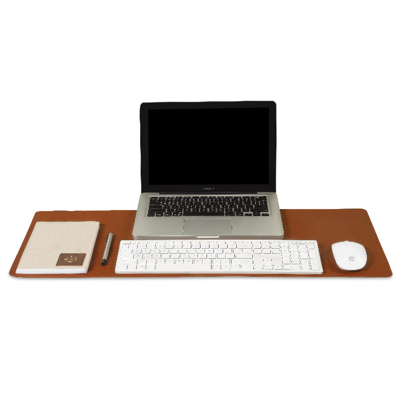 Brown leather desk mat with laptop, keyboard, mouse, notebook, and pen on a minimalist workspace setup.