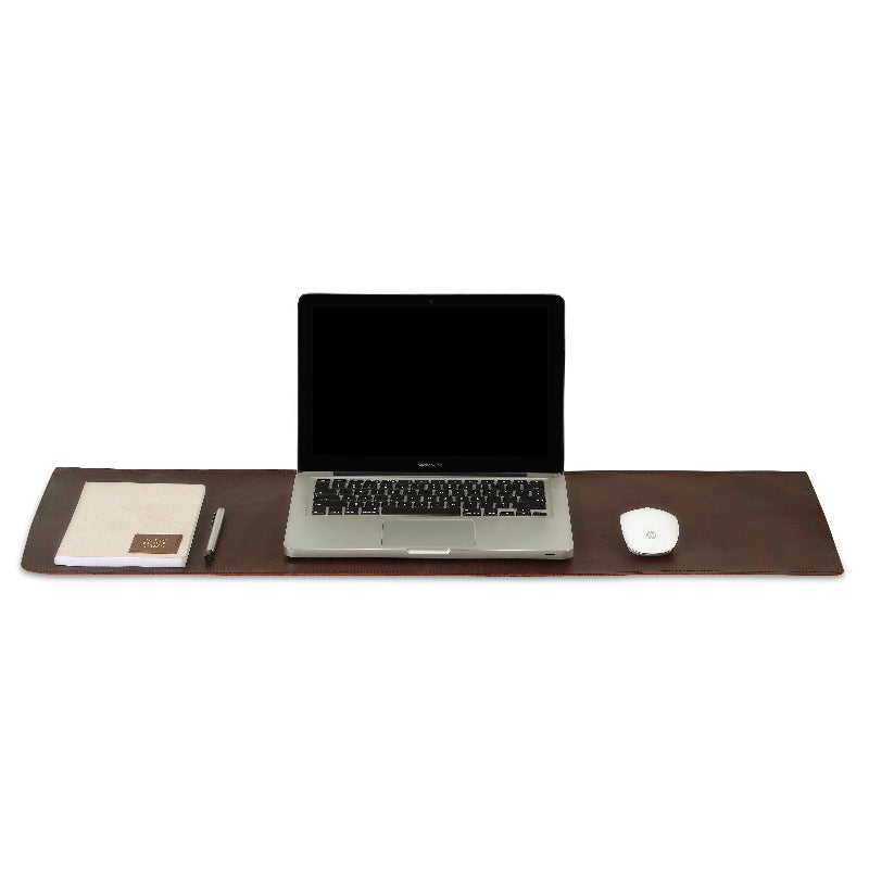 Laptop on a brown leather desk with a mouse and notebook on a white background
