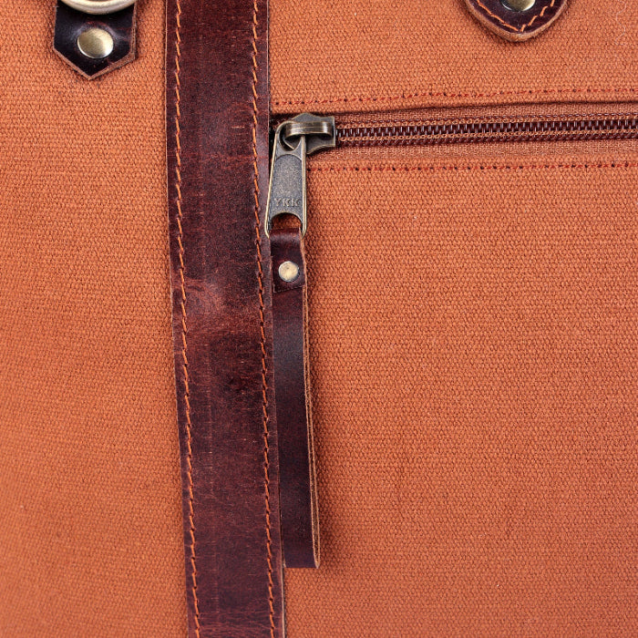Close-up of a brown leather bag with a zipper and metal clasp.