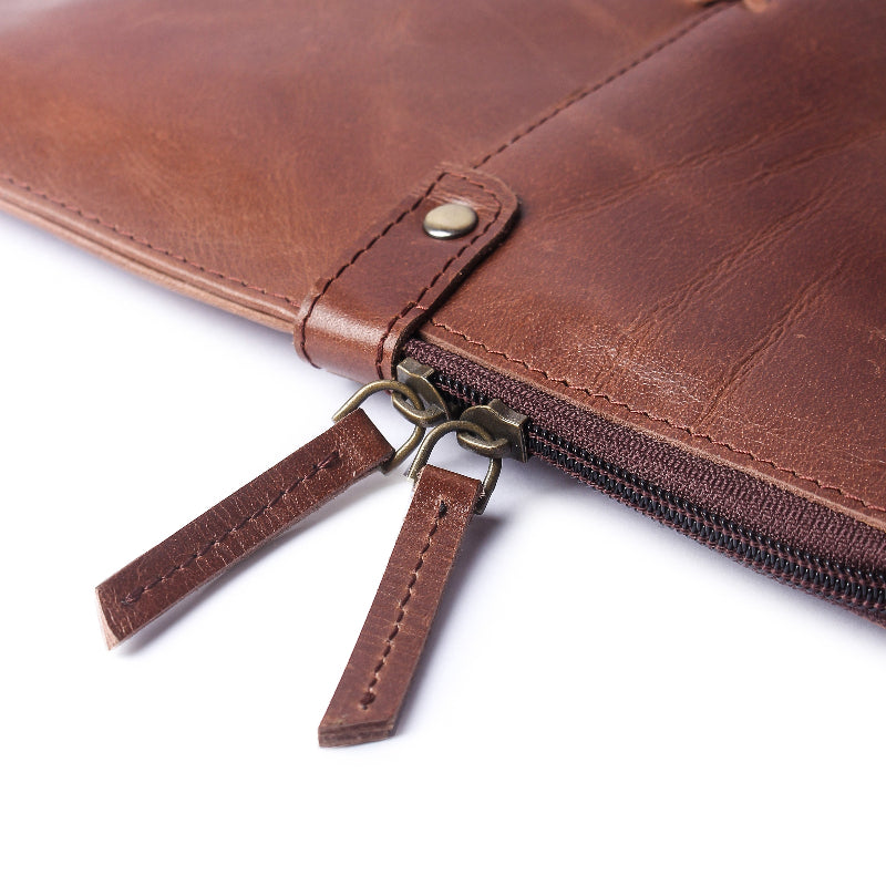 Close-up of a brown leather pouch with zipper on a white background
