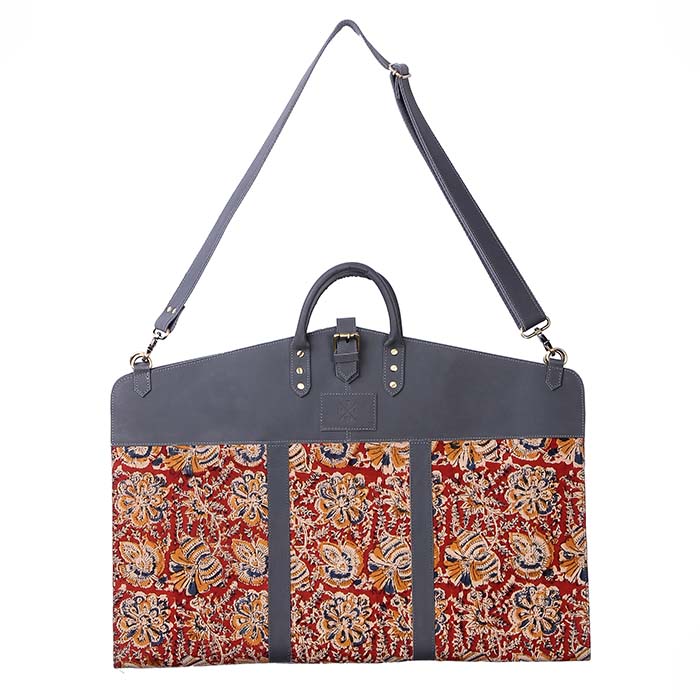 Handcrafted garment bag with grey leather detailing and multicolor floral printed fabric, featuring dual handles and a detachable shoulder strap.