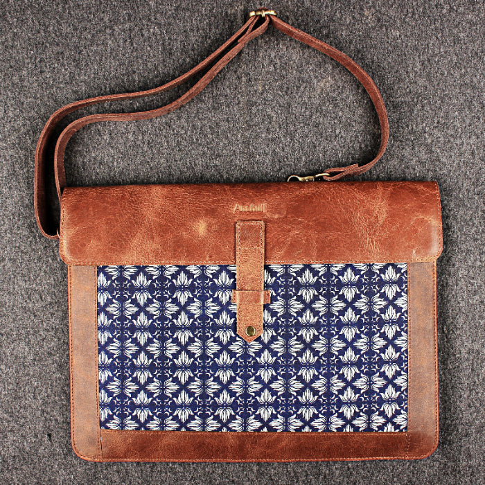 Brown leather bag with blue patterned flap on a gray background