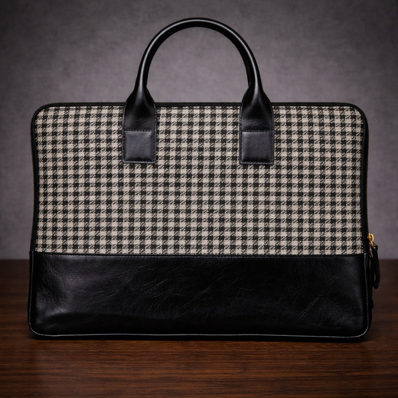 Black and gray checkered briefcase canvas with leather accents on a wooden surface.