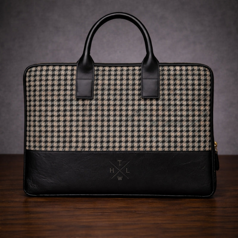 Houndstooth patterned briefcase with canvas & black leather accents on a wooden surface.