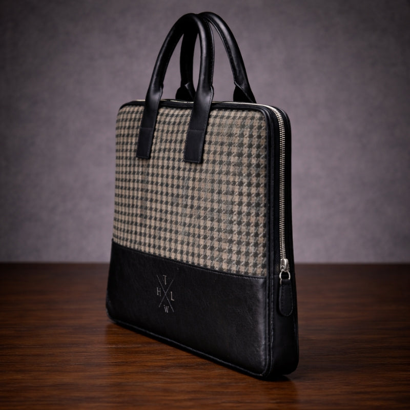 Houndstooth patterned briefcase canvas with black leather accents on a wooden surface.