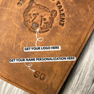 Brown leather passport cover with embossed logo and text on a wooden surface