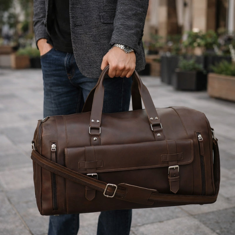 Person holding a brown leather duffel bag outdoors