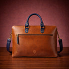 Brown leather briefcase with blue handles and strap on a wooden surface and brown background