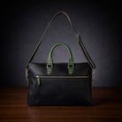 Black leather handbag with green accents on a dark background