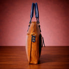 Brown leather handbag with blue handles on a wooden surface and red background