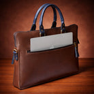 Brown leather briefcase with a laptop inside on a wooden surface