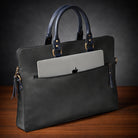 Black leather briefcase with a laptop inside on a wooden surface and dark background