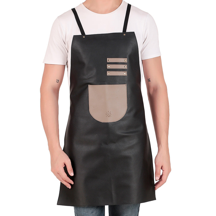 Man wearing a black leather apron with beige front pocket and adjustable shoulder straps, standing against a white background.