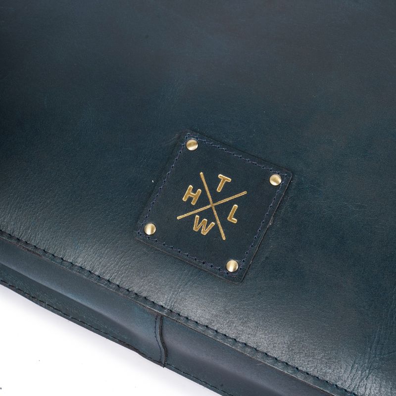 Close-up of leather handbag logo and stitching.