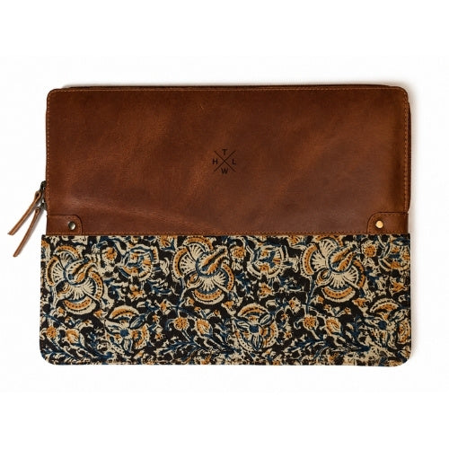 A rectangular zippered pouch or sleeve with a smooth brown leather top half and a dark patterned fabric bottom half featuring beige and gold floral motifs, shown on a white background.