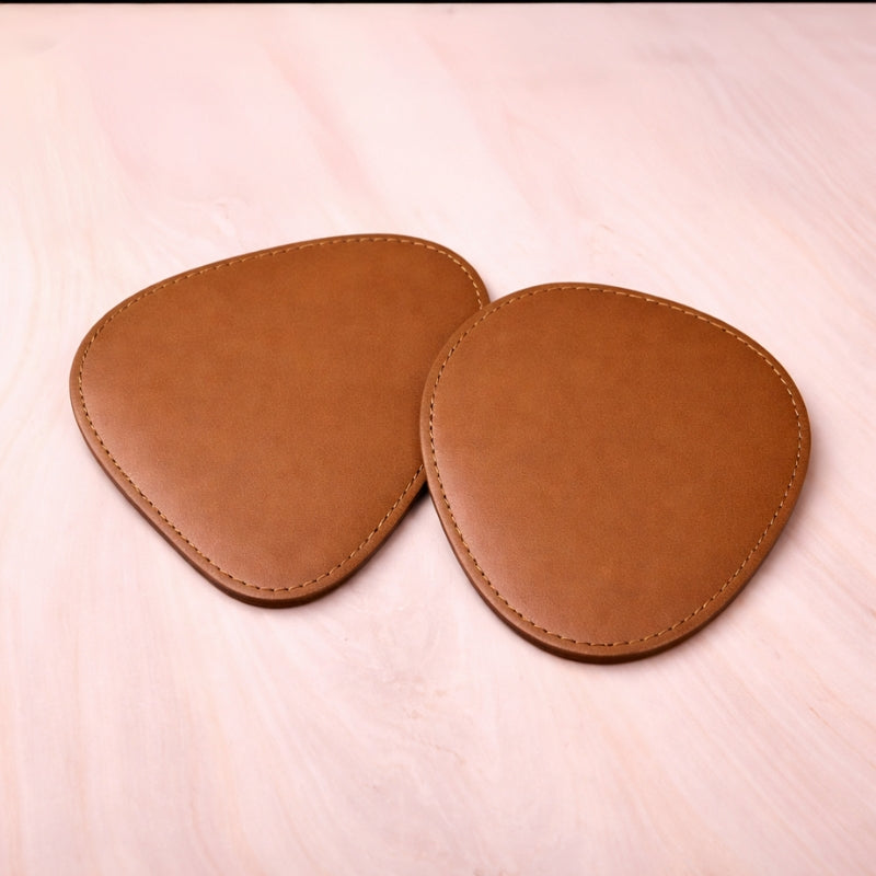 Pair of brown leather coasters on a light pink surface