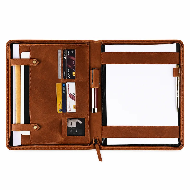 Brown leather portfolio organizer opened to show card slots, document compartments, pen holders, and a notepad.