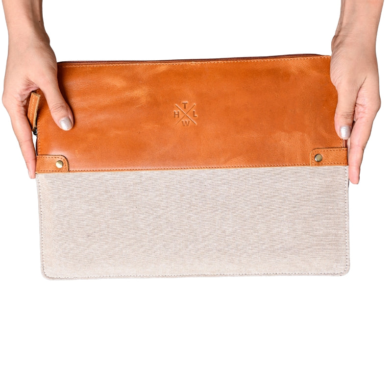 Two tone sleeve with brown leather top and beige fabric bottom held on white background.