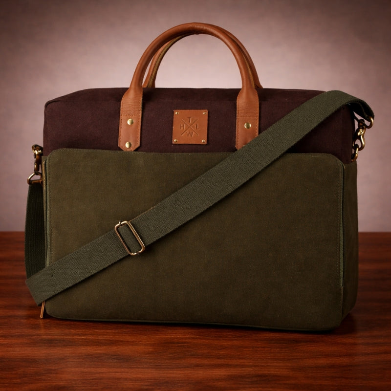 Two-toned brown and green leather  & canvas bag with a visible brand logo on a wooden surface.