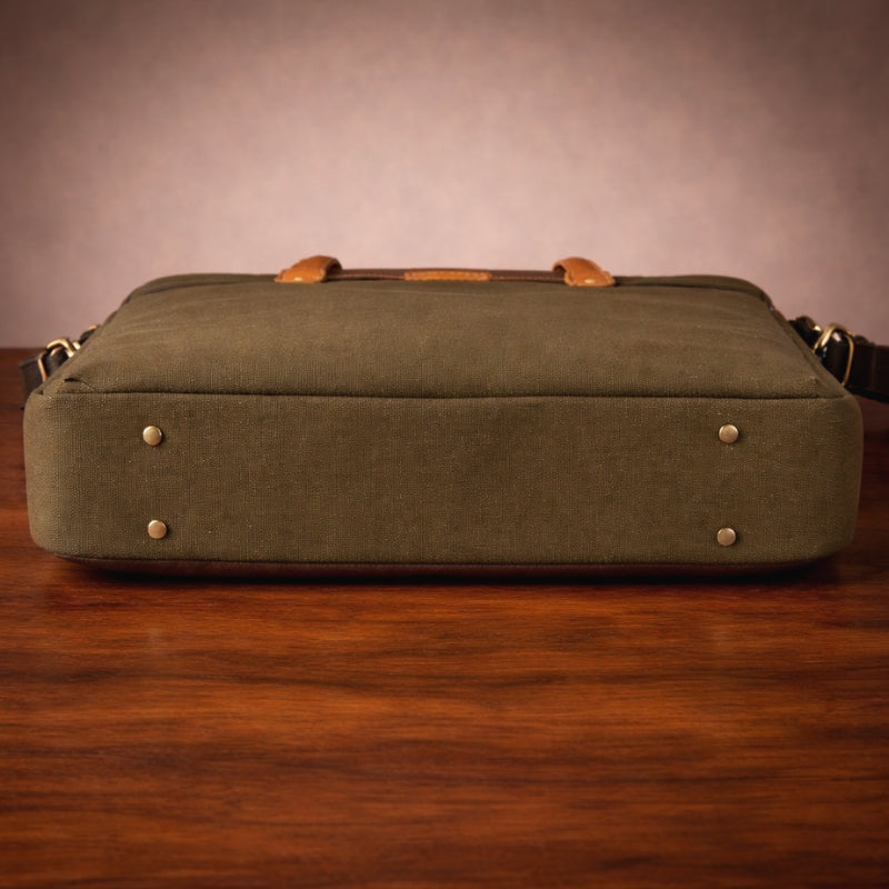 Green canvas bag with canvas & leather straps on a wooden surface