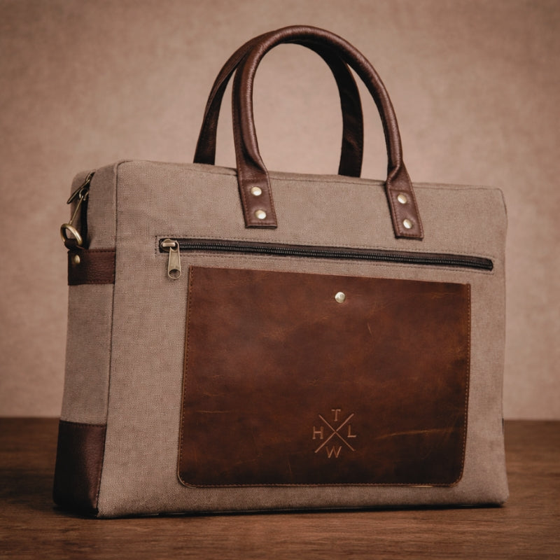 Brown canvas &  leather and fabric handbag with visible branding on a wooden surface.