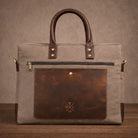 Brown leather and canvas briefcase with a visible brand logo on a brown background