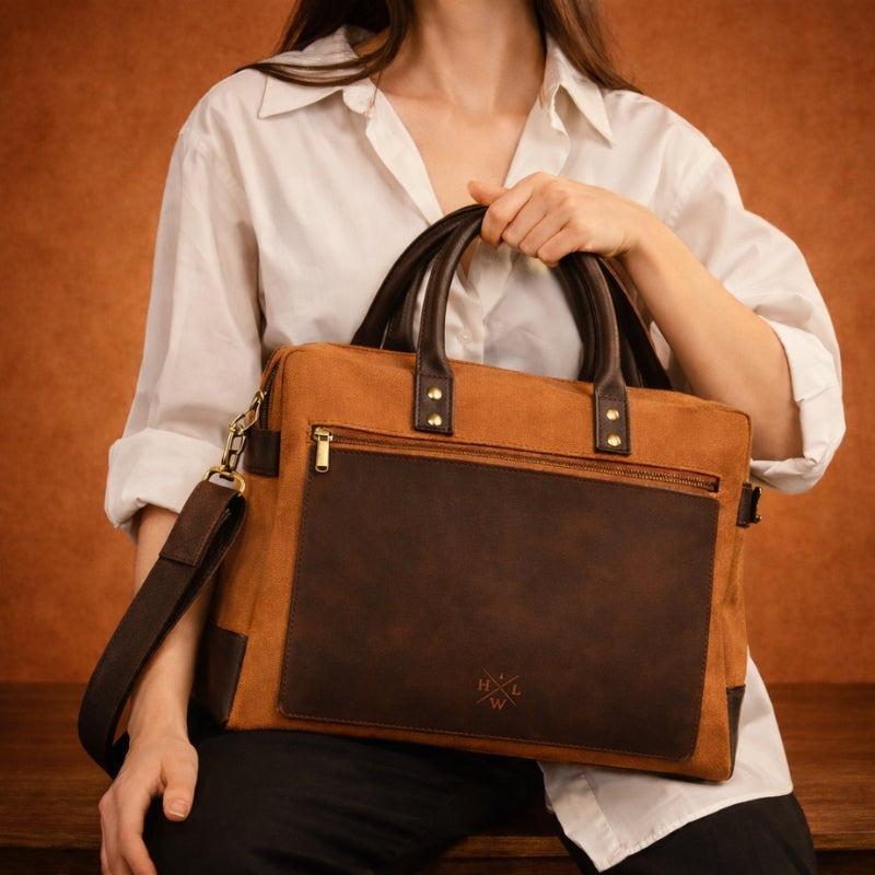 Person holding a orange canvas & leather briefcase with a visible brand logo against a warm-toned background
