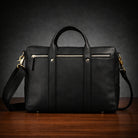 Black leather bag with gold hardware on a wooden surface and dark background