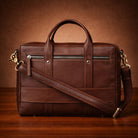 Brown leather bag with a shoulder strap on a wooden surface
