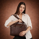 Woman holding a brown leather bag against a brown background