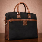 Black canvas  bag with brown leather accents on a wooden surface and brown background