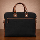 Black canvas  bag with brown leather handles and trim on a wooden surface.
